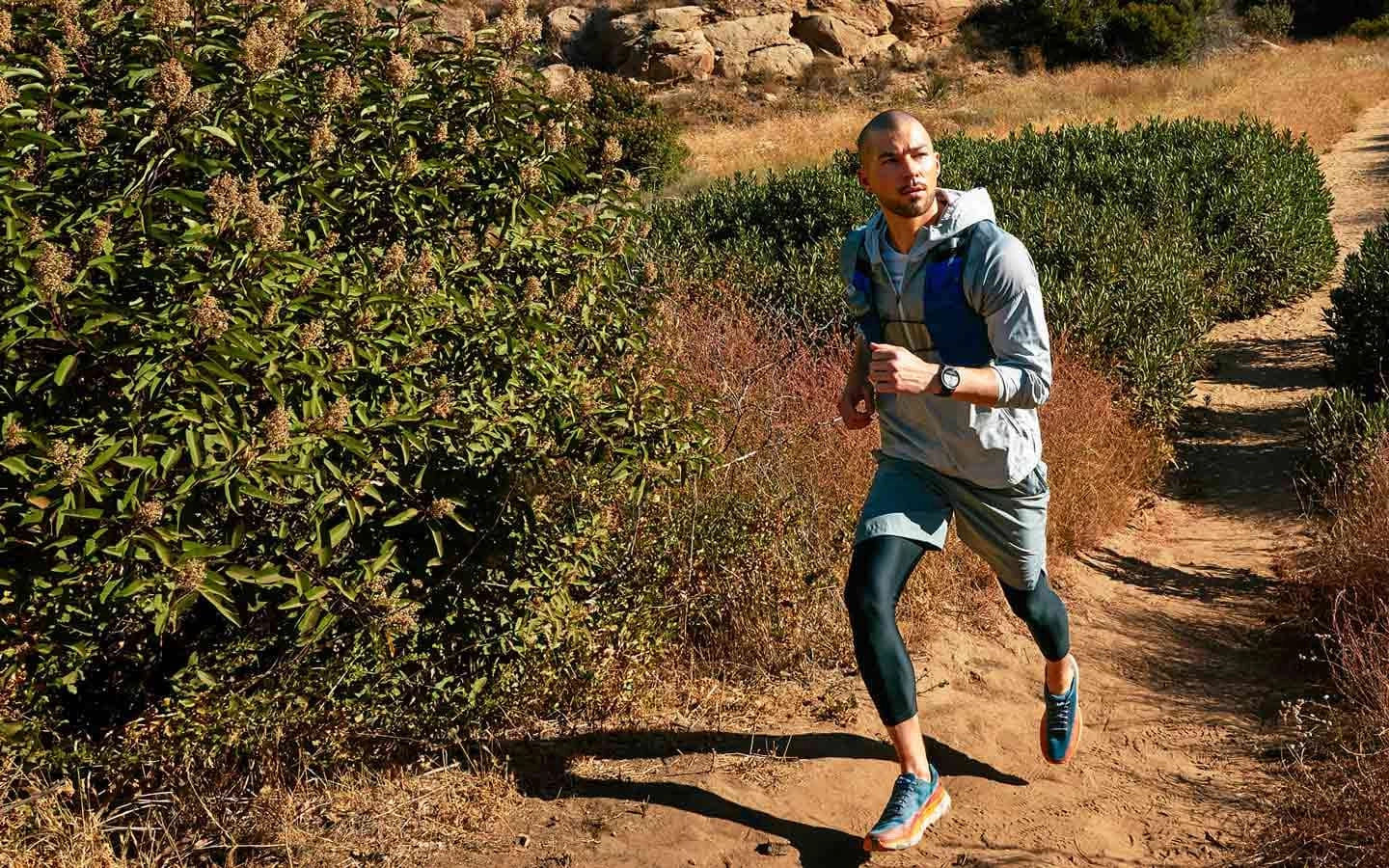 A man hiking downhill with a Watch5 Pro on his wrist displaying the navigation feature.